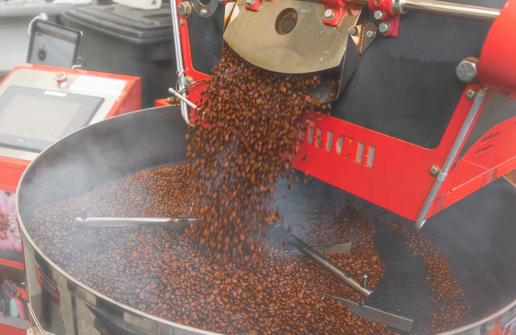 Coffee beans pour from a roaster into a cooling pan.