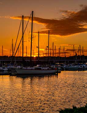 Boats moored at Oak Harbor Marina with an orange sky from a setting sun behind them.