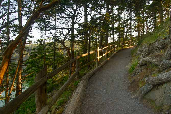 A trail with a wooden fence overlooks Deception Pass