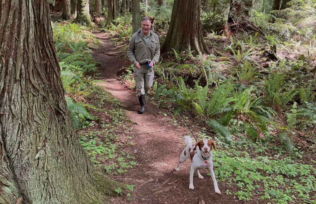 Man walking dog on  Camano Ridge trail, photo by Janet Wingett