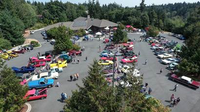 Aerial view of cars parked at the Camano Center and people looking at them.