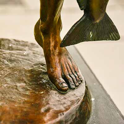 Sculpture of a Native American man focusing on one bare foot.