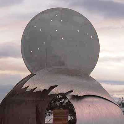 A round metal moon rises atop metal waves in a sculpture in Oak Harbor