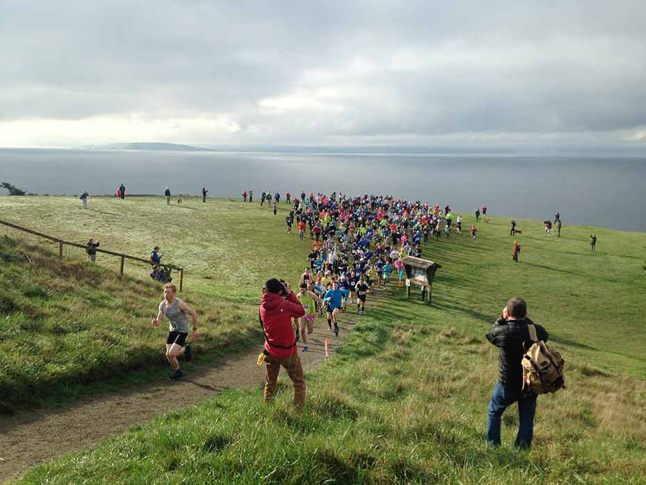 A crowd of runners with Puget Sound in the background.