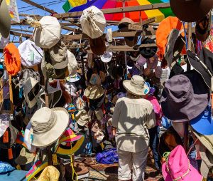 A woman stands surrounded by hats .
