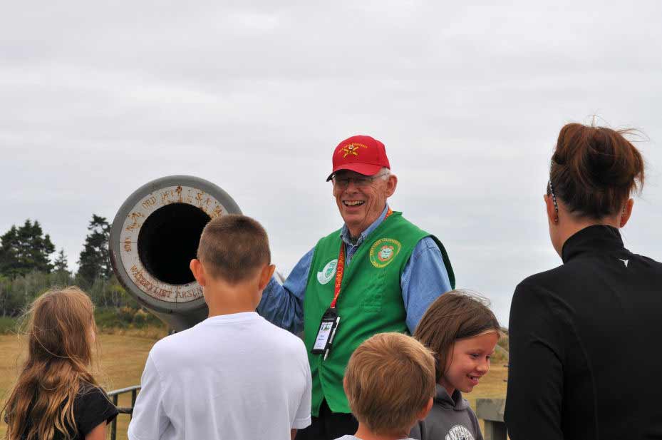 Man stands next to a cannon and talks with a group of kids.