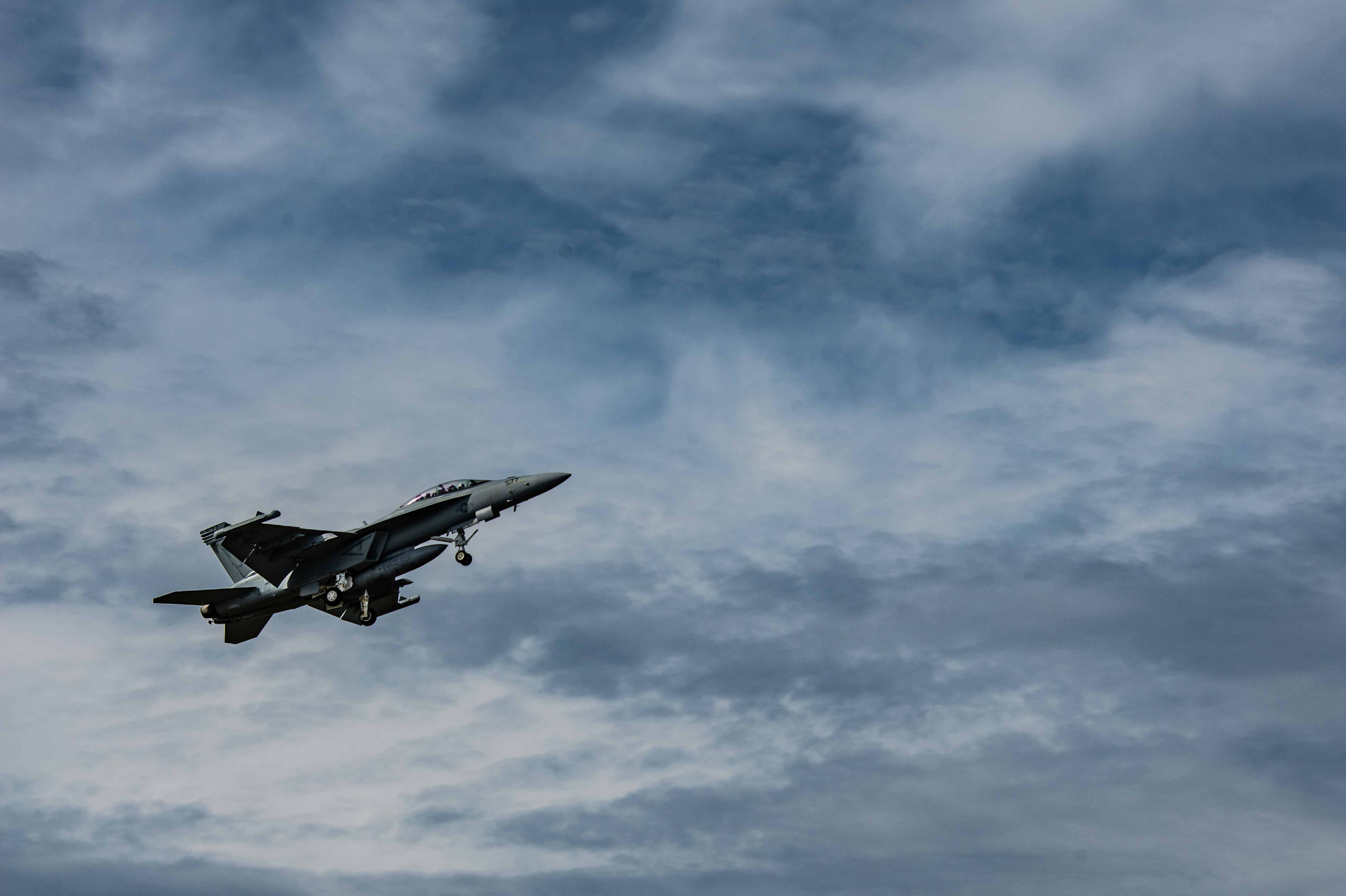 A military jet, the EA-18G growler in mid-air, as seen from the ground.