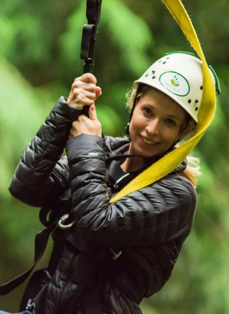 Woman smiles as she goes zip lining.
