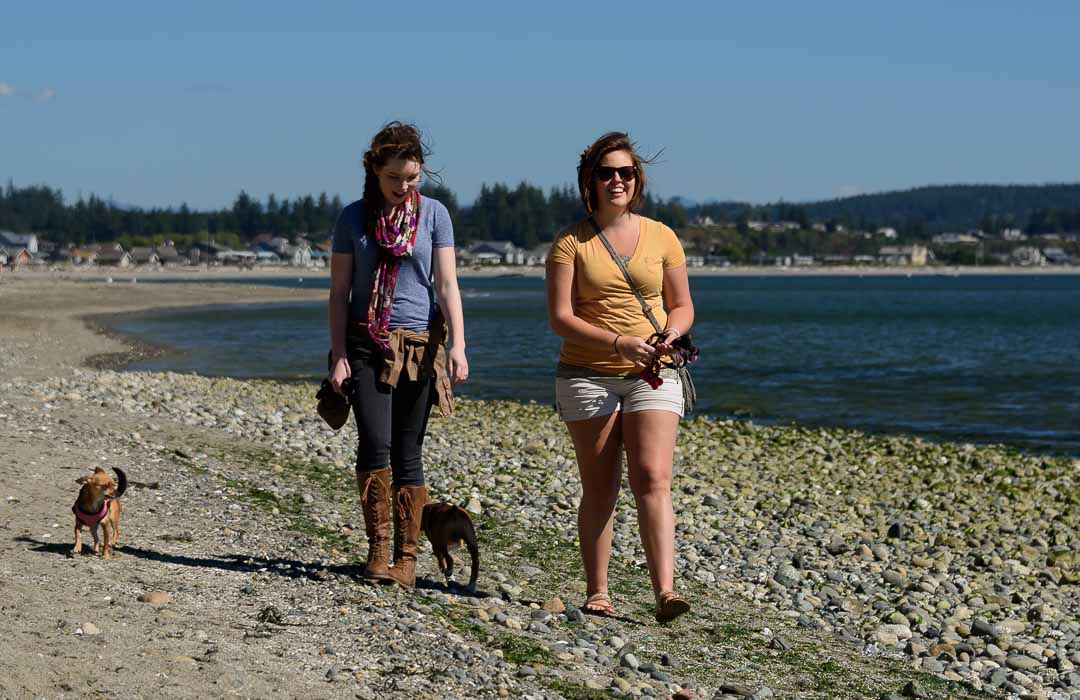 Two women walk their dogs on Double Bluff Beach