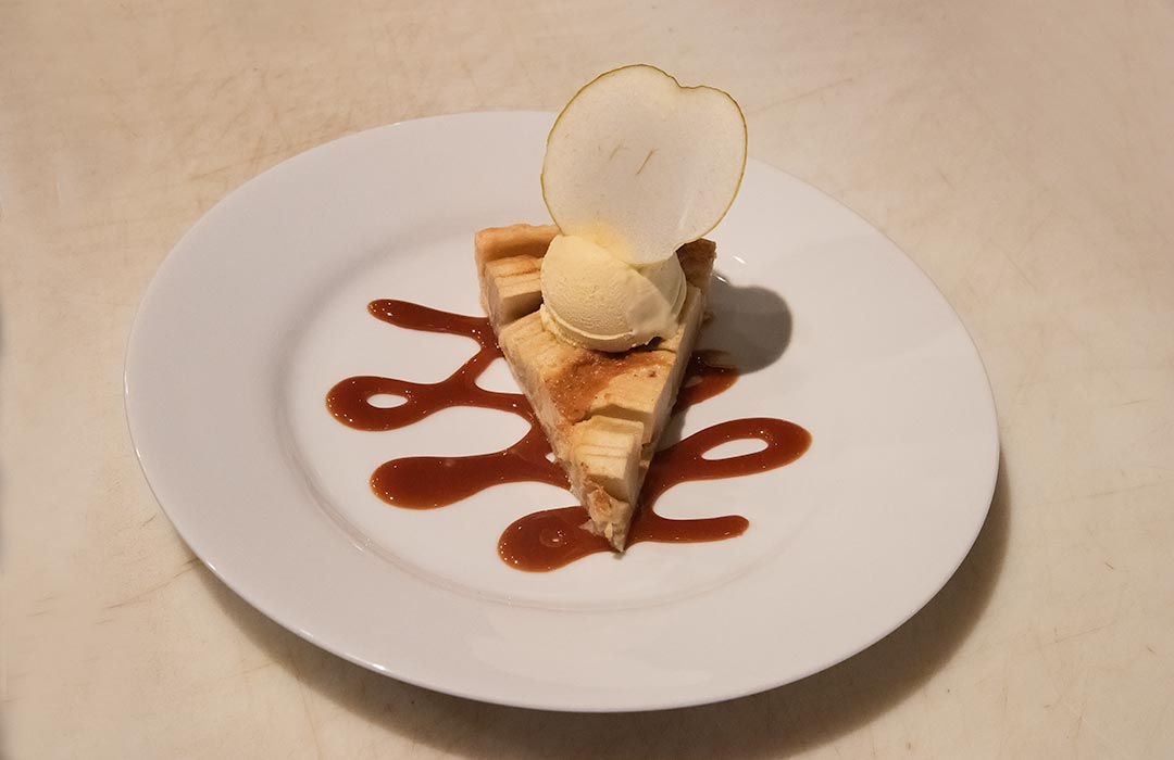 Slice of pie with a scoop of ice cream and a slice of apple in the ice cream
