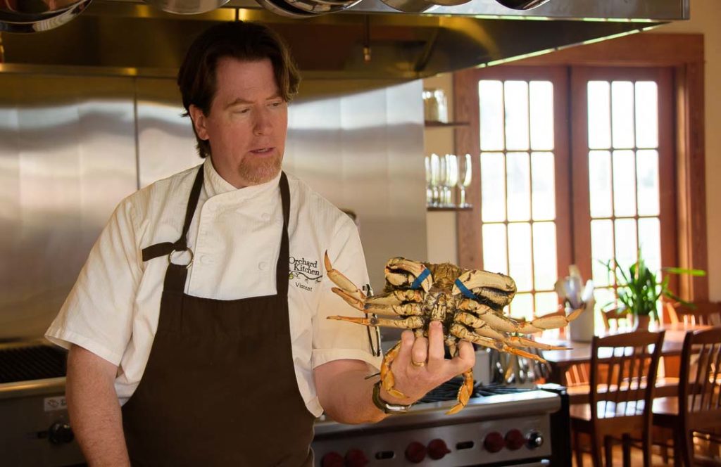 Chef Vincent holds a live Dungeness Crab in one hand.