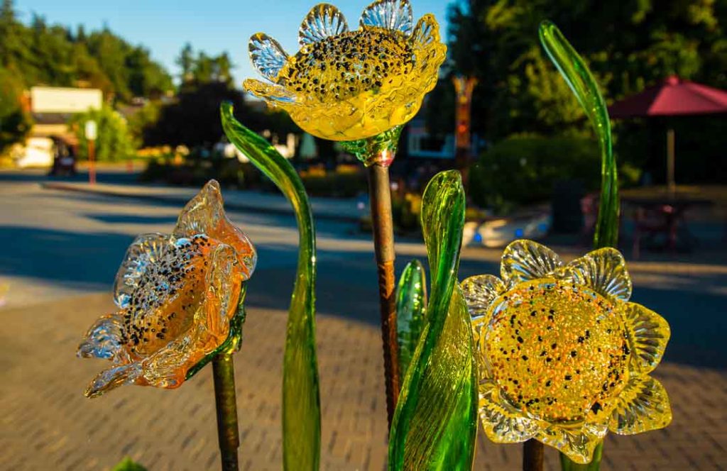 Flowers made of glass are displayed on a city street.
