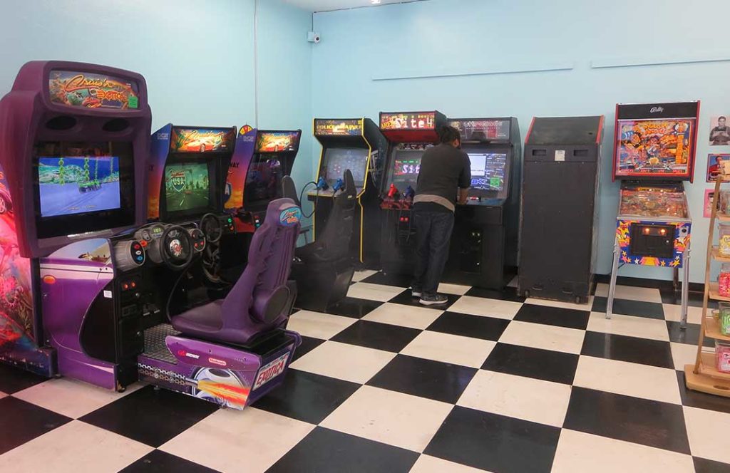 Several arcade games and one person playing one of the games.