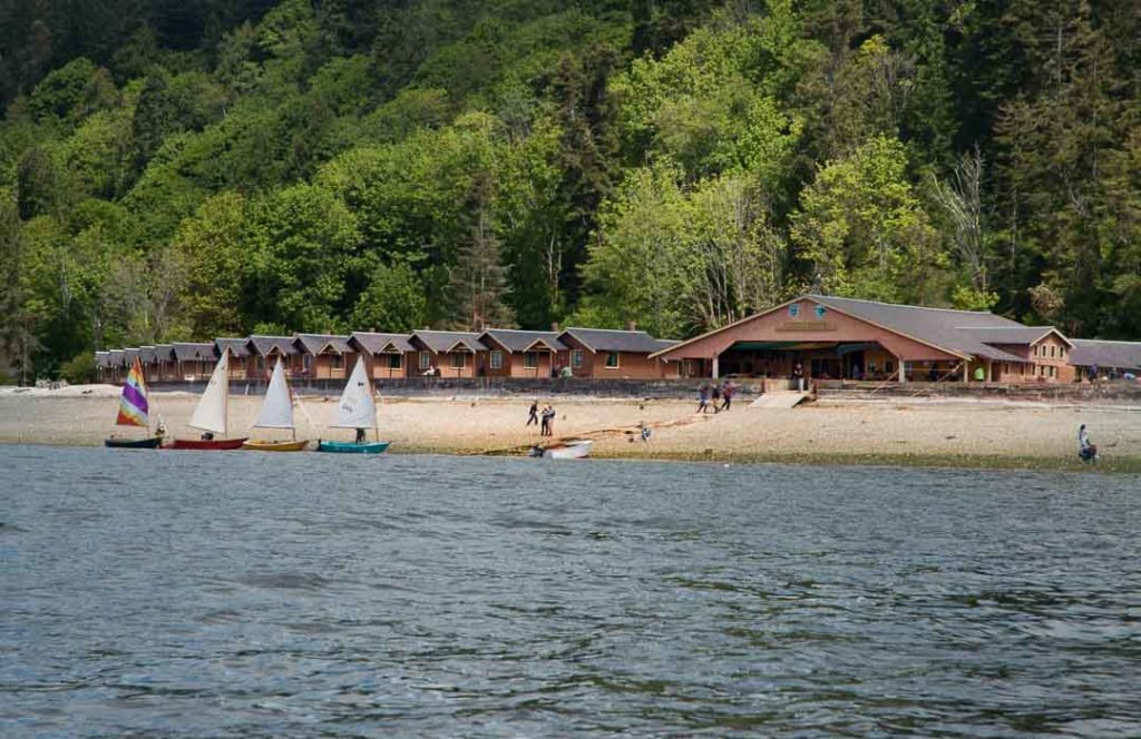 Boats sail in front of the cabins at Cama Beach State Park