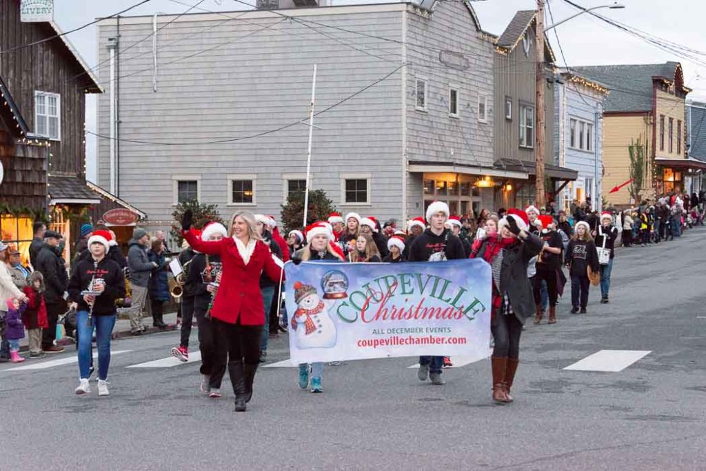People hold a banner that says "Christmas" as they walk in a parade in Coupeville.