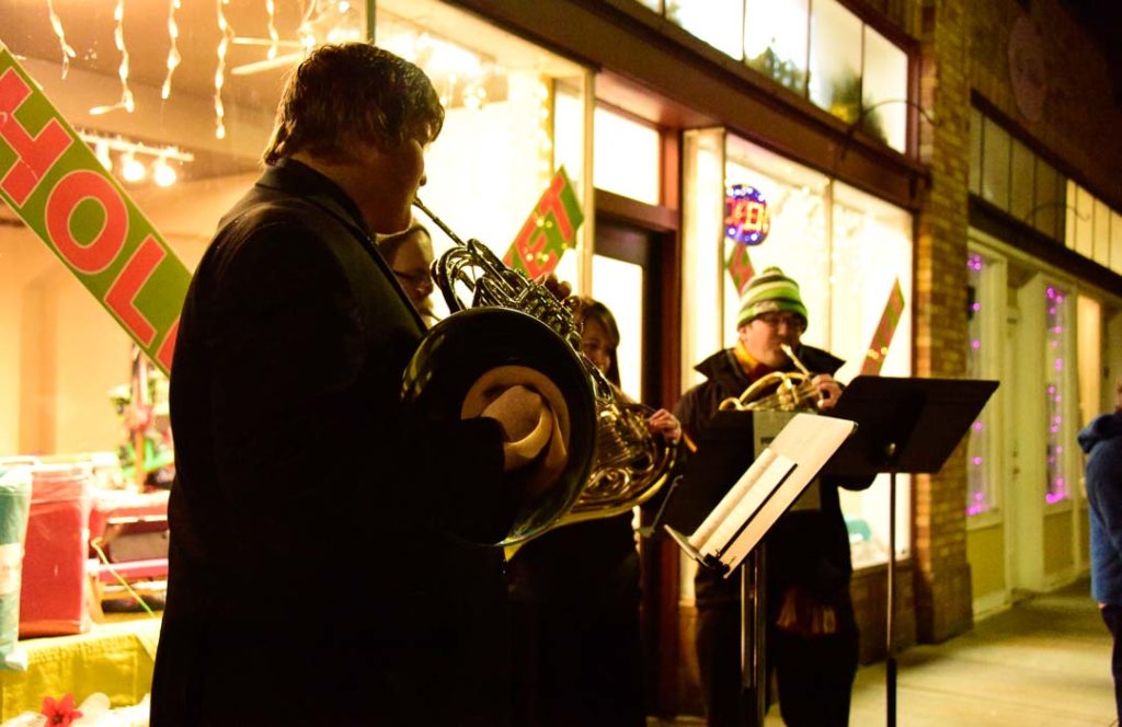 A brass quartet performs along a city street at night.