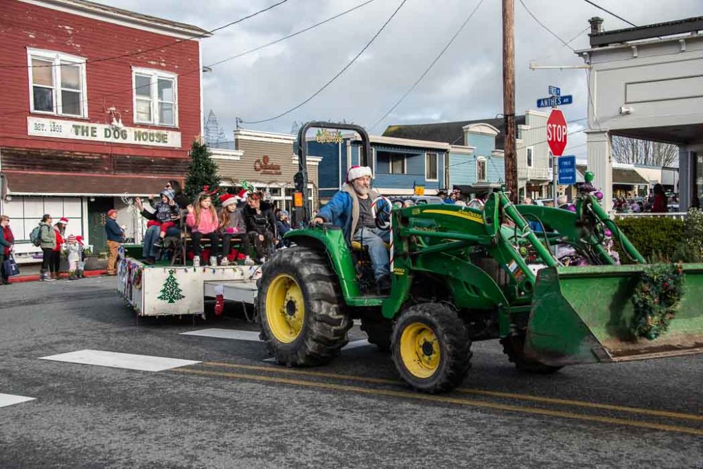 A green tractor pulls a float in a holiday parade through Langley