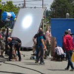 People moving lights and other equipment while making a movie.