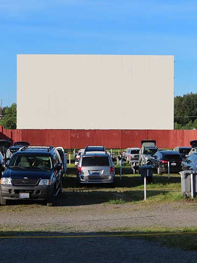 Cars parked in front of a blank drive-in screen before the show.