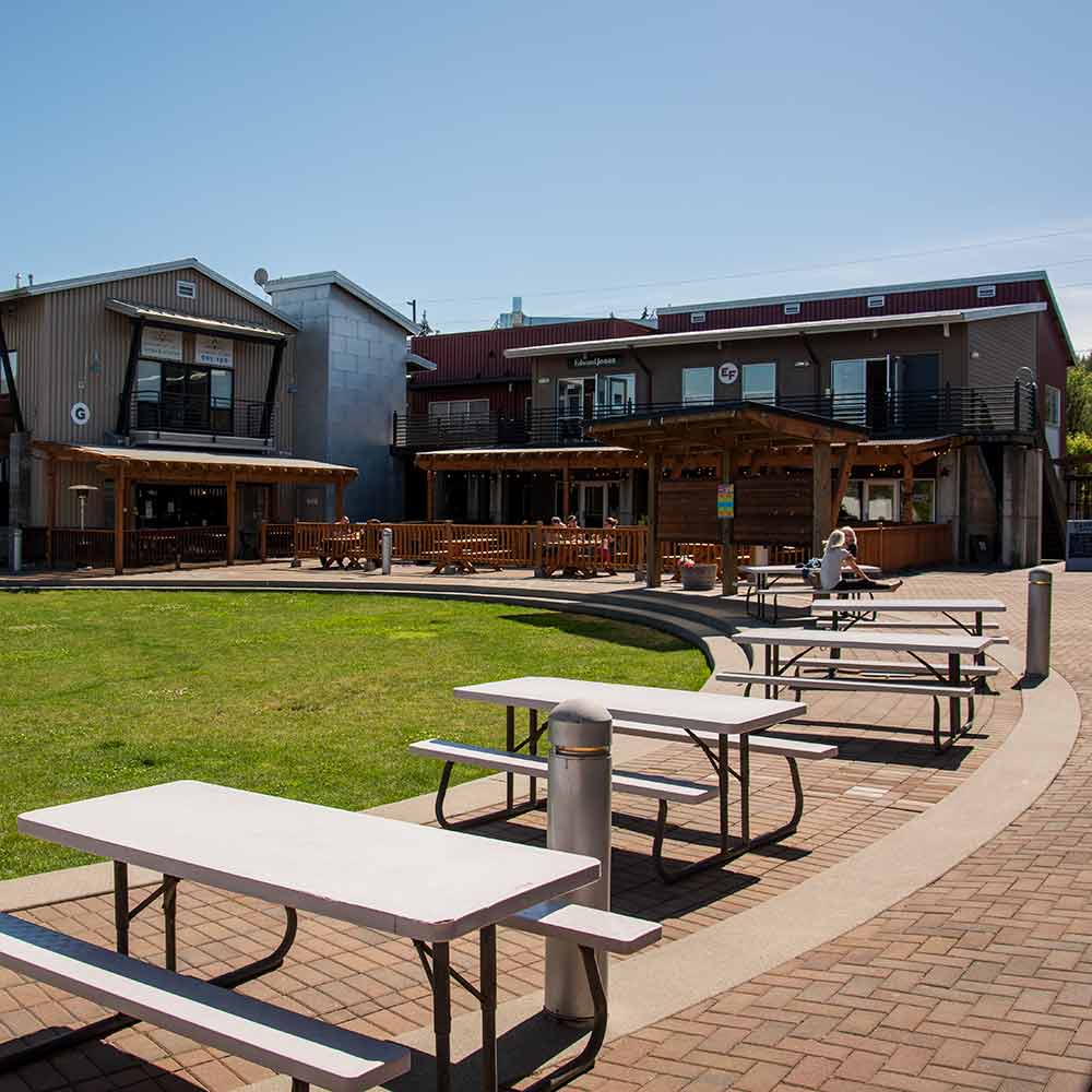 An open area with picnic tables surrounded by two story buildings.