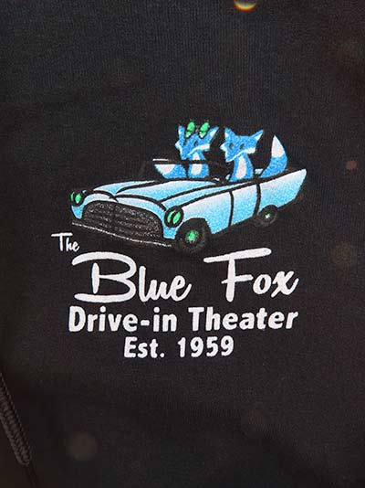 Logo of two blue foxes in an old convertible.  It says, "The Blue Fox Drive-in Theater, Est. 1959"