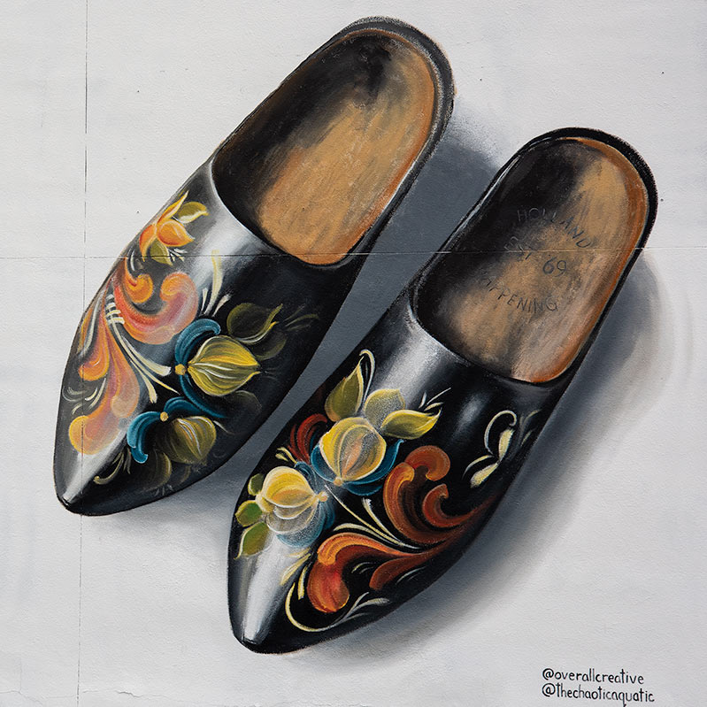 Detailed and lifelike mural of two wooden shoes decorated with flowers