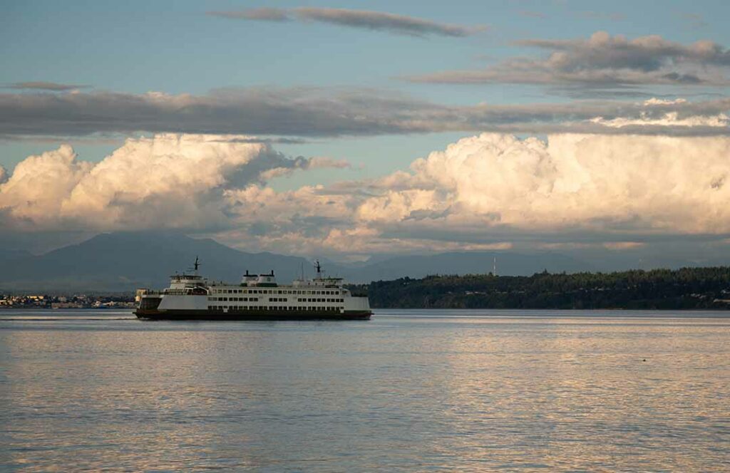 Washington State Ferry in open water under bright white clouds.