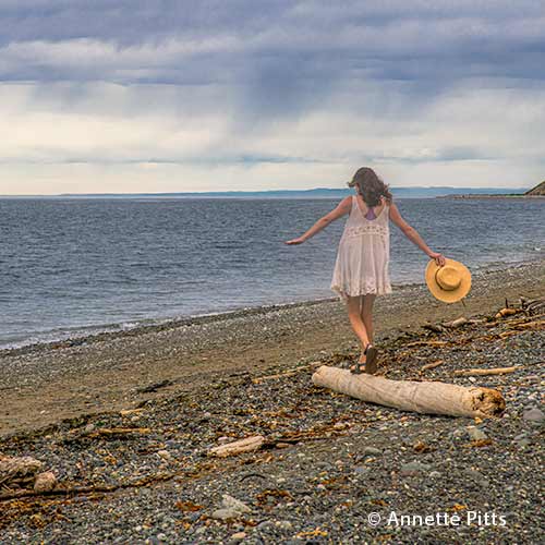 Woman walking atop a driftwood log at Ebey's Landing