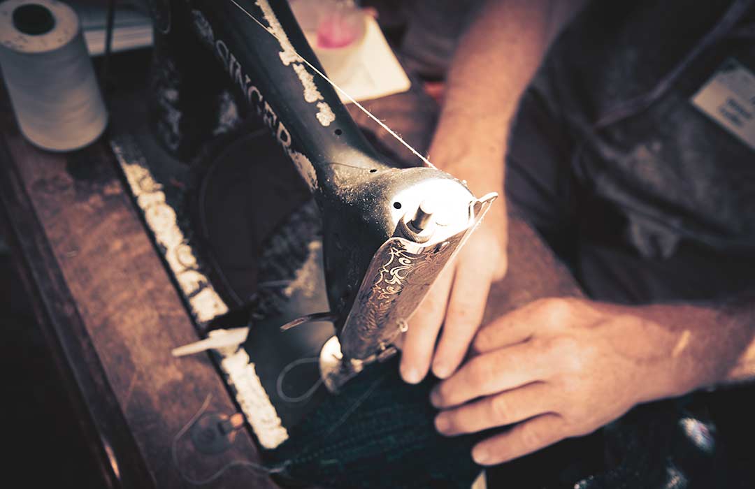 Close up of two hands working at an old sewing machine