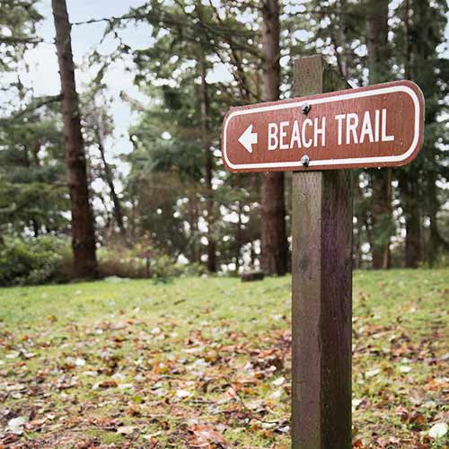 Wooden sign says "Beach Trail" and points where to go.