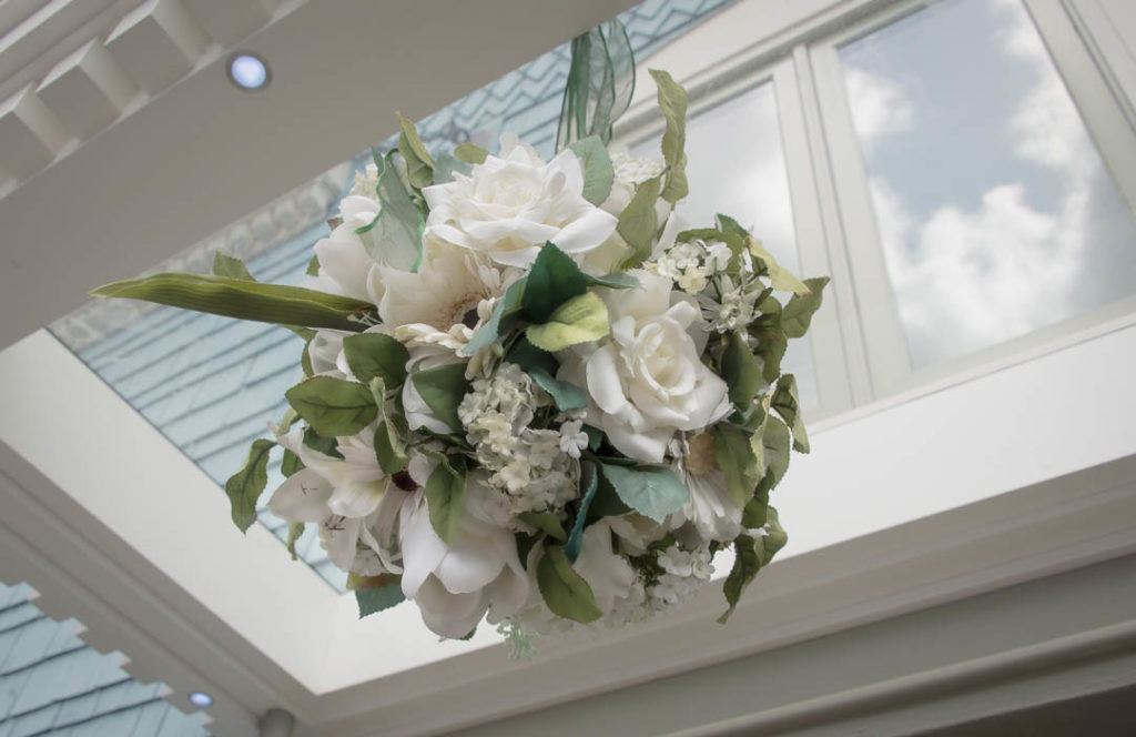 Flowers arranged in a ball hanging from a ceiling.