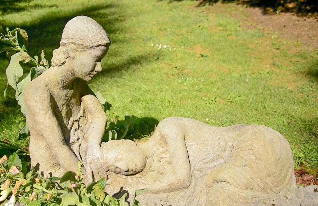 Stone carving of a couple enjoying the grass. One is resting their head on the other's lap.