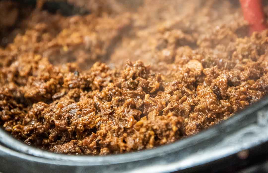 Close view of a crockpot filled with a ground-beef based chili.