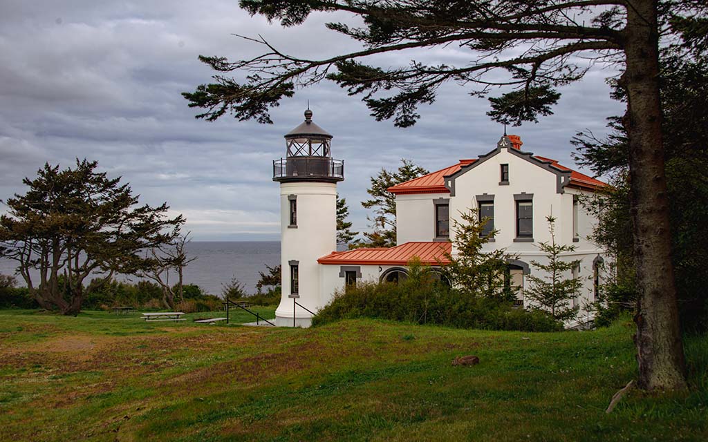 Lighthouse from the outside. It is Spanish Mission style with a red tile roof. The light tower is not much taller than the house.