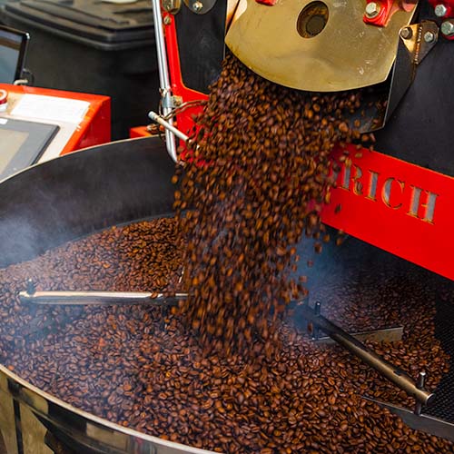 Coffee beans pour from a roaster into a cooling pan.