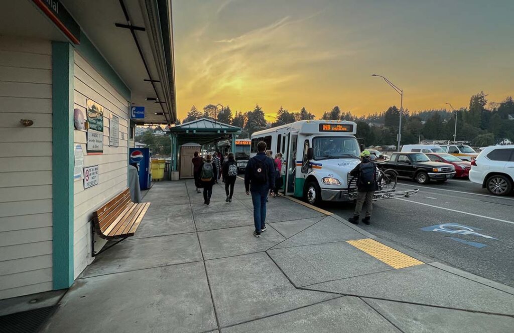 The sun is setting behind waiting busses.