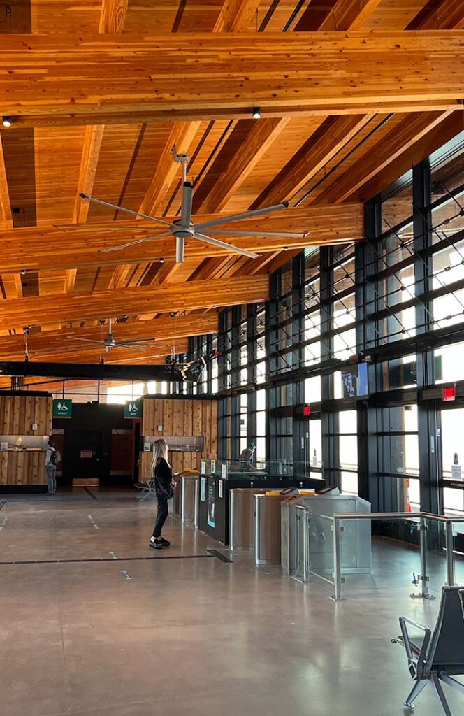 A lobby with turnstiles and a striking wood ceiling.
