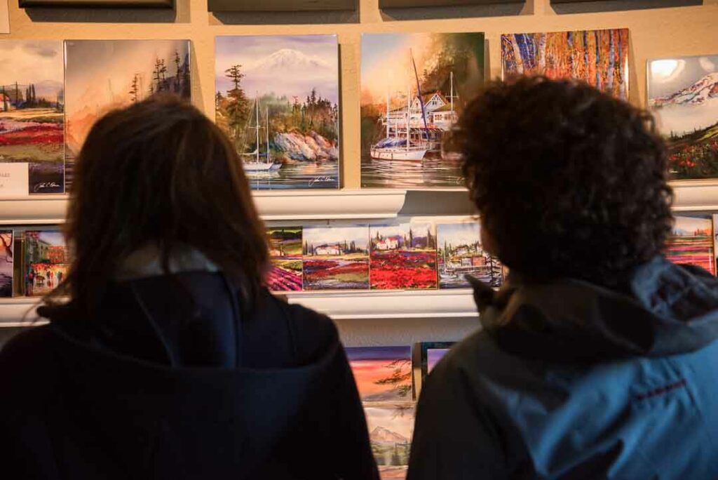 Backs of two people looking at paintings