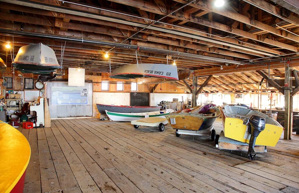 Various small boats in a large wooden building.