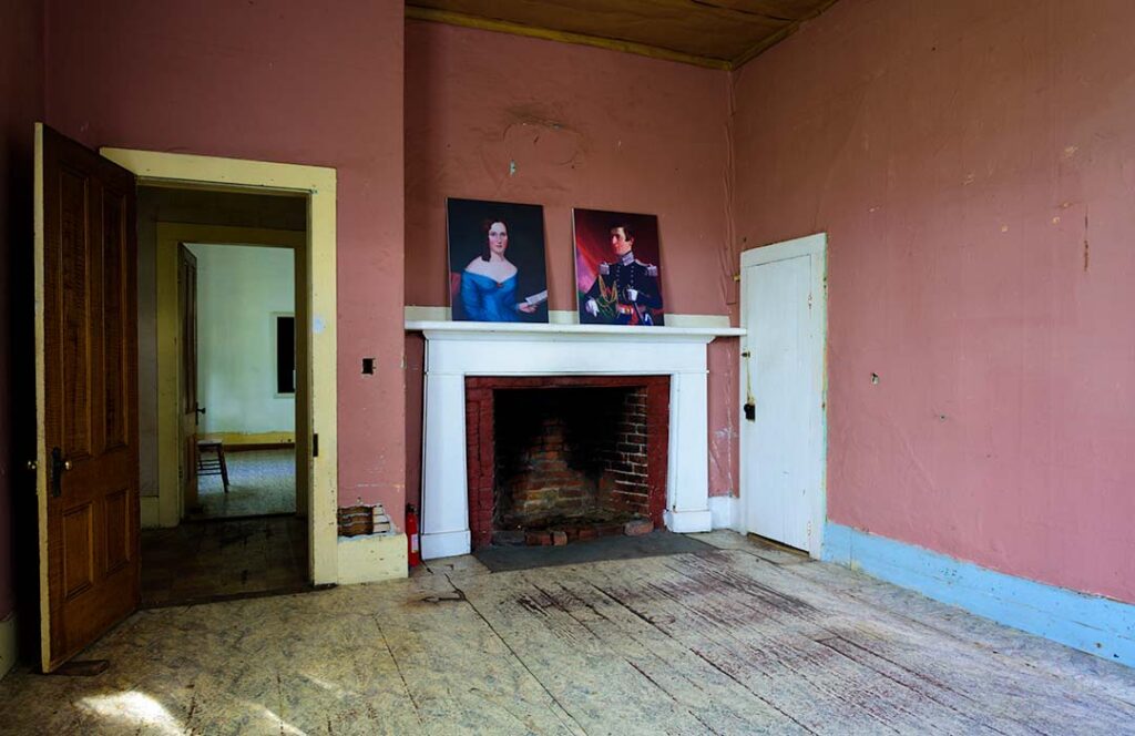 The Haller House Living room showing how it had deteriorated.  Portraits of the Hallers are on the fireplace mantle.