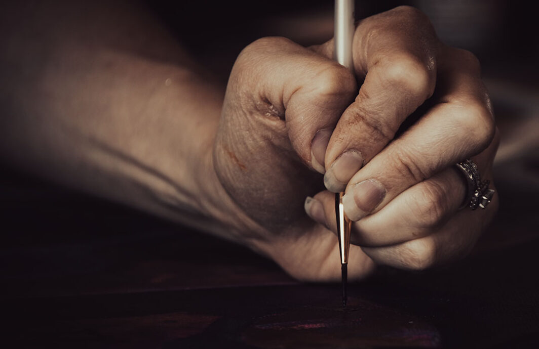 Close up of a woman's hand holding a paint brush and painting.