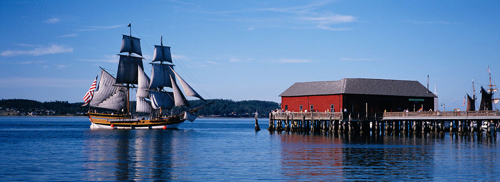 Old-fashioned sailing ship pulling up to an old wooden wharf.