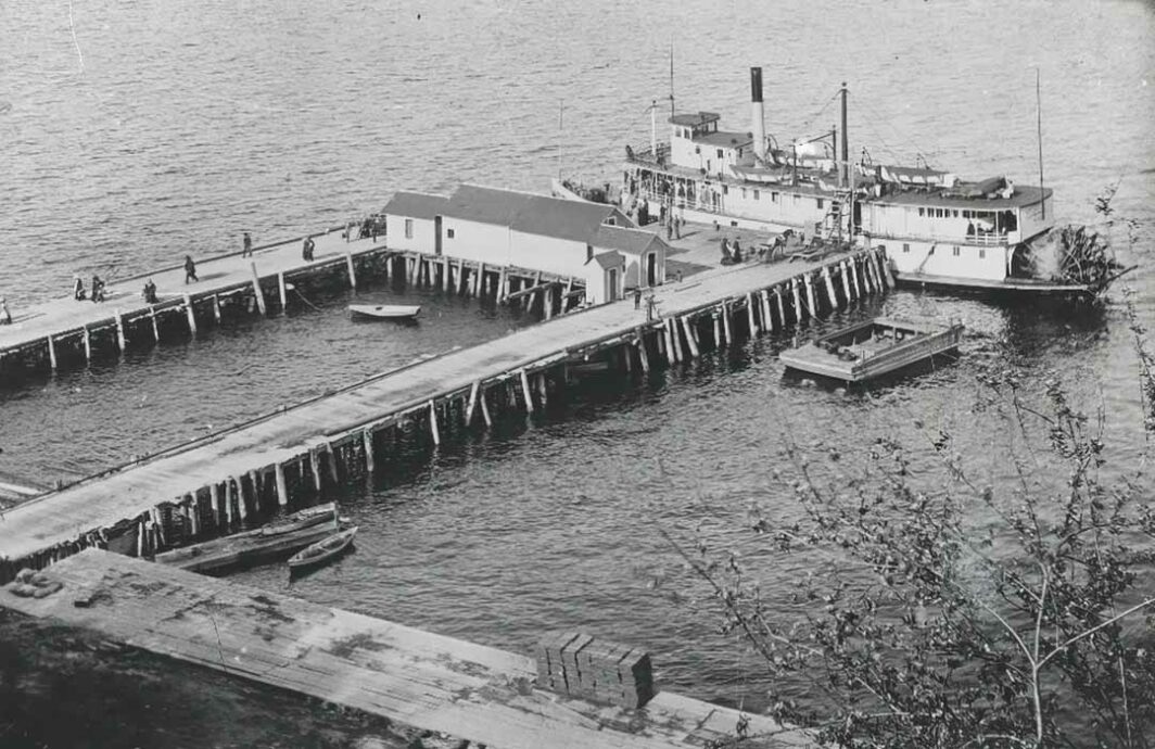 Old photo of a steam ship and a large wooden dock.