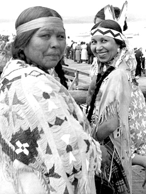 Two women in traditional Native American clothing pose for the camera.
