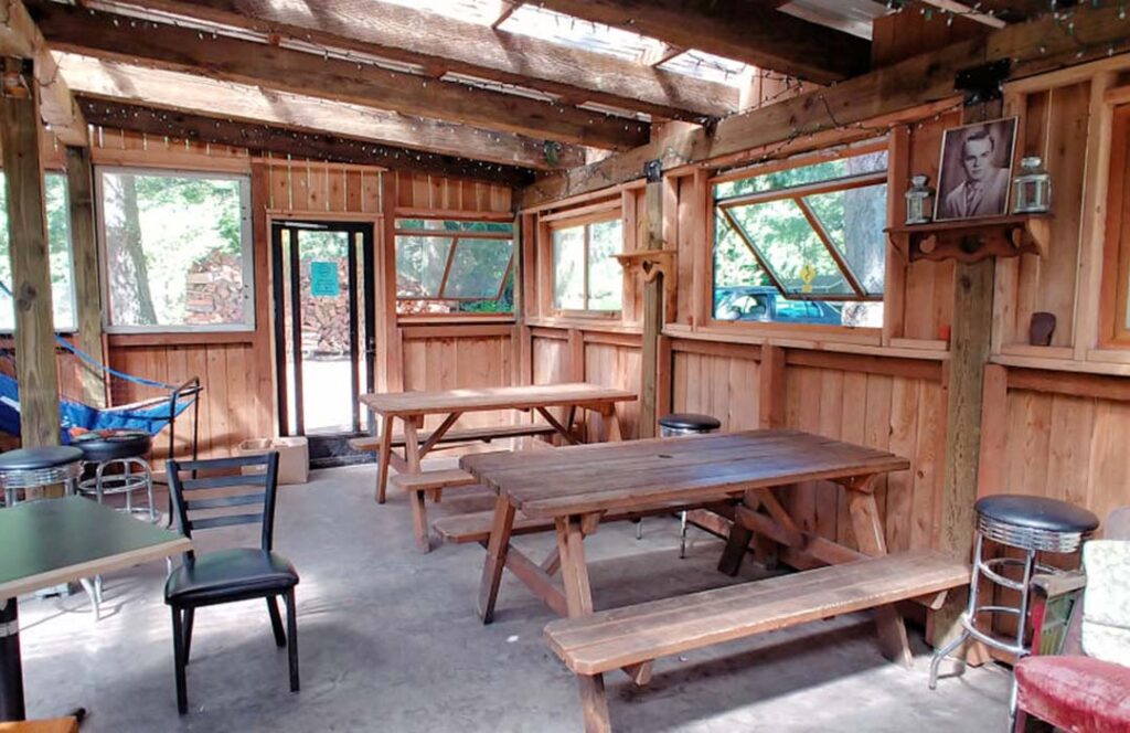 Wooden picnic tables and benches inside a wooden room.