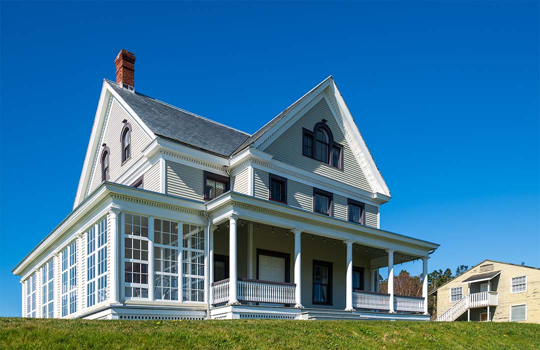 An old 3 story house sitting on a hill.