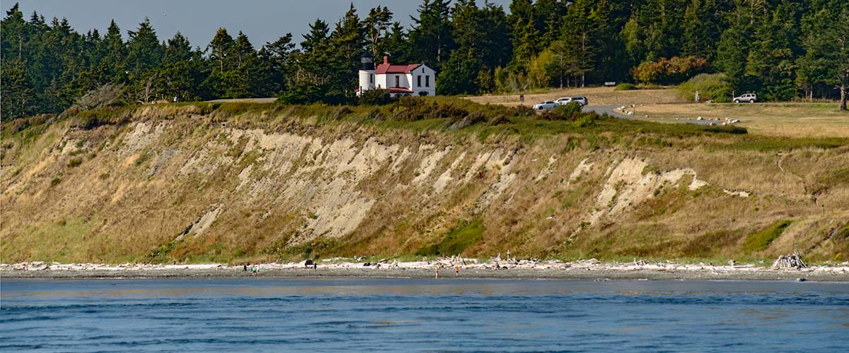 A lighthouse on a bluff and a beach below the bluff.