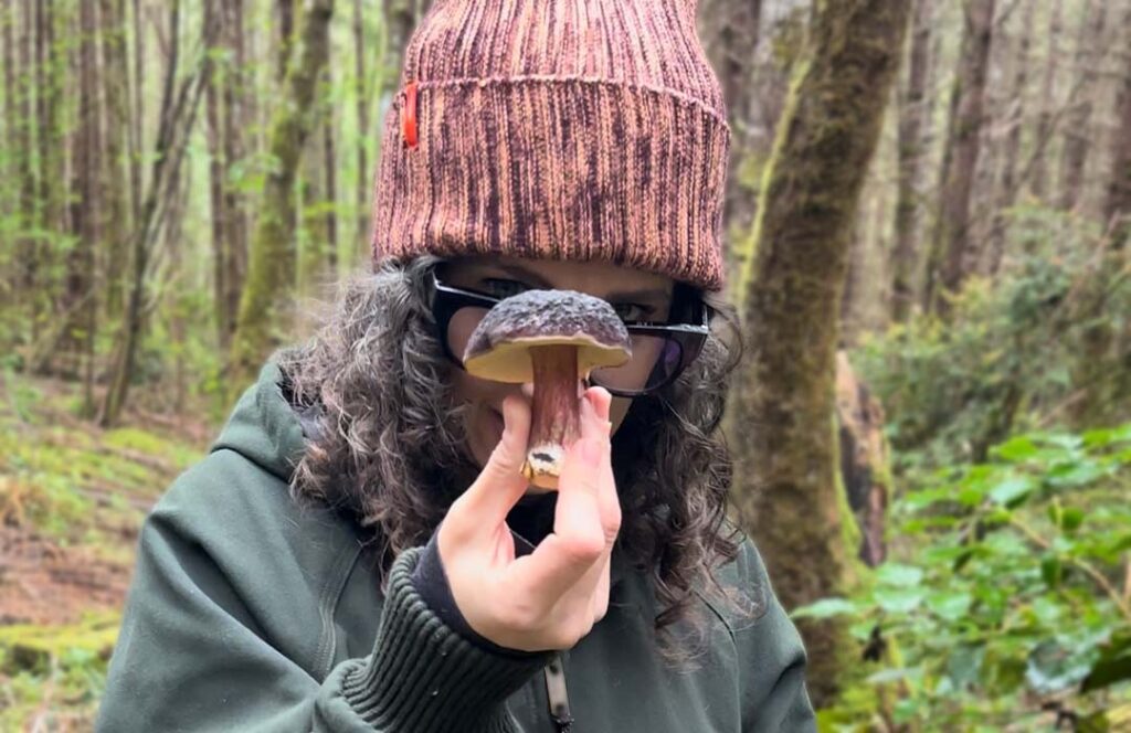 Woman staring intently at a mushroom in her hand.