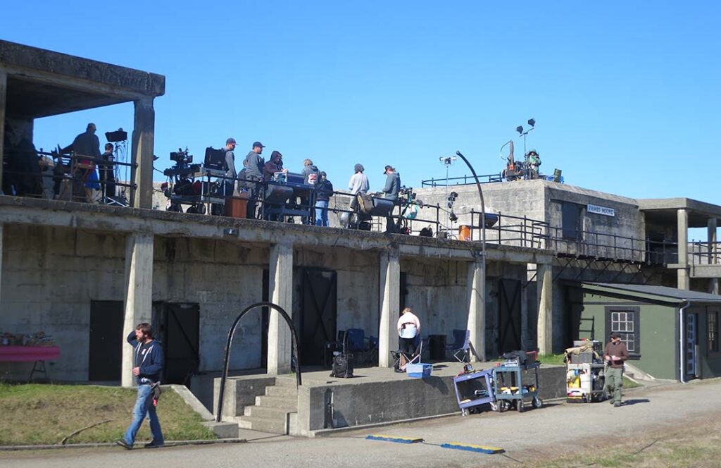 A group of people with lights and other fillmaking equipment working on a large concrete structure that is Fort Casey.